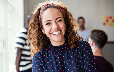 Woman with curly hair and red headband smiling
