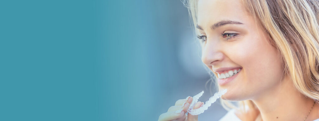 Girl smiling and holding an invisalign